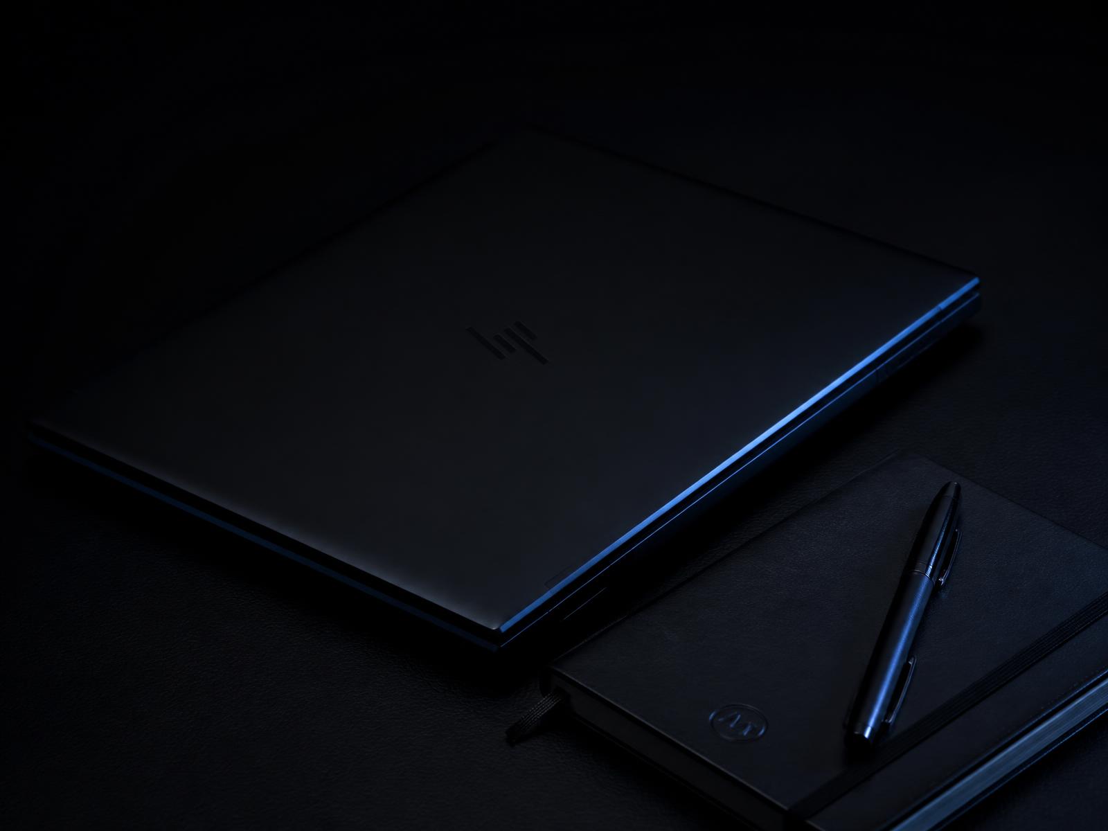 Laptop and notebook on a dark desk